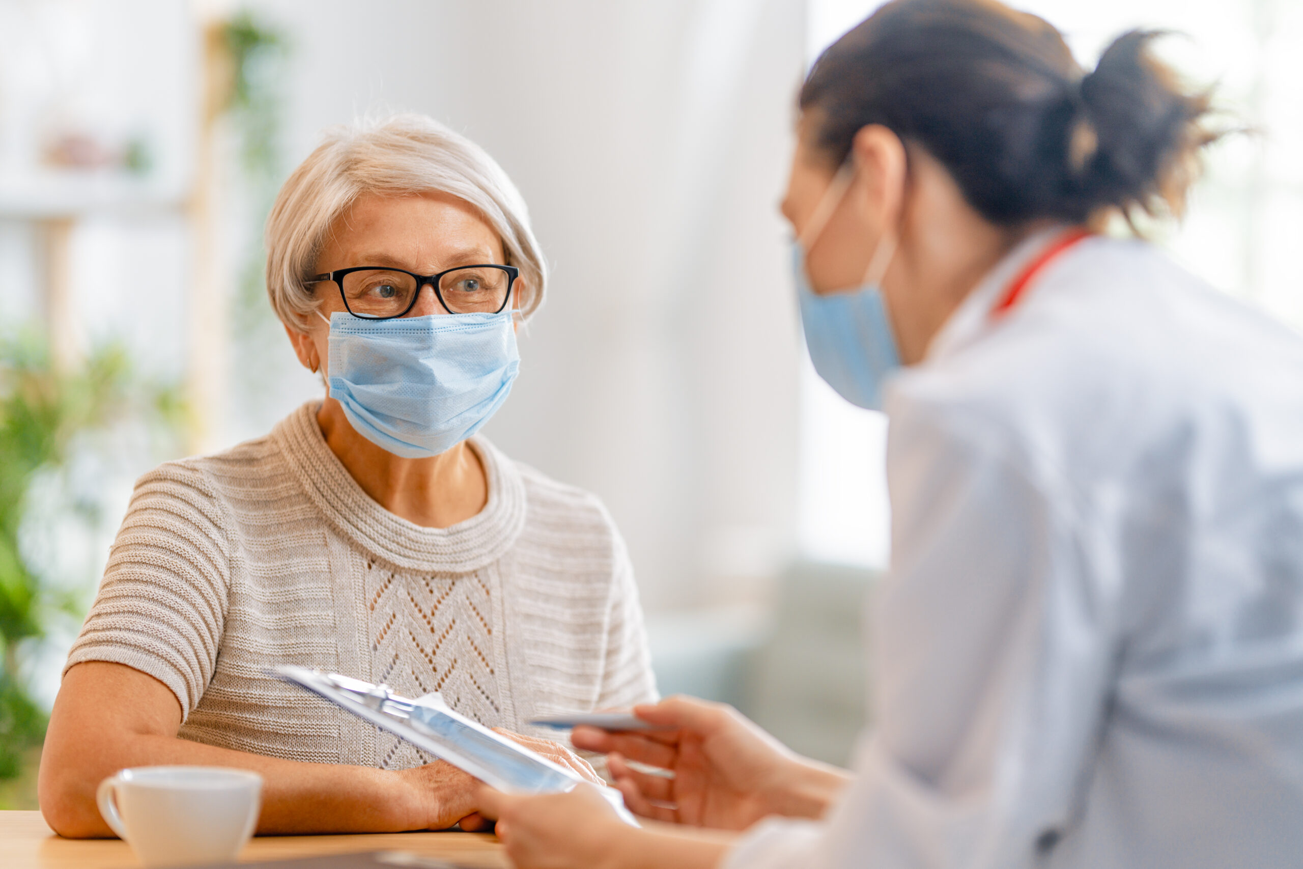 Doctor and senior woman wearing facemasks during coronavirus and flu outbreak. Virus protection. COVID-2019. Taking on masks.