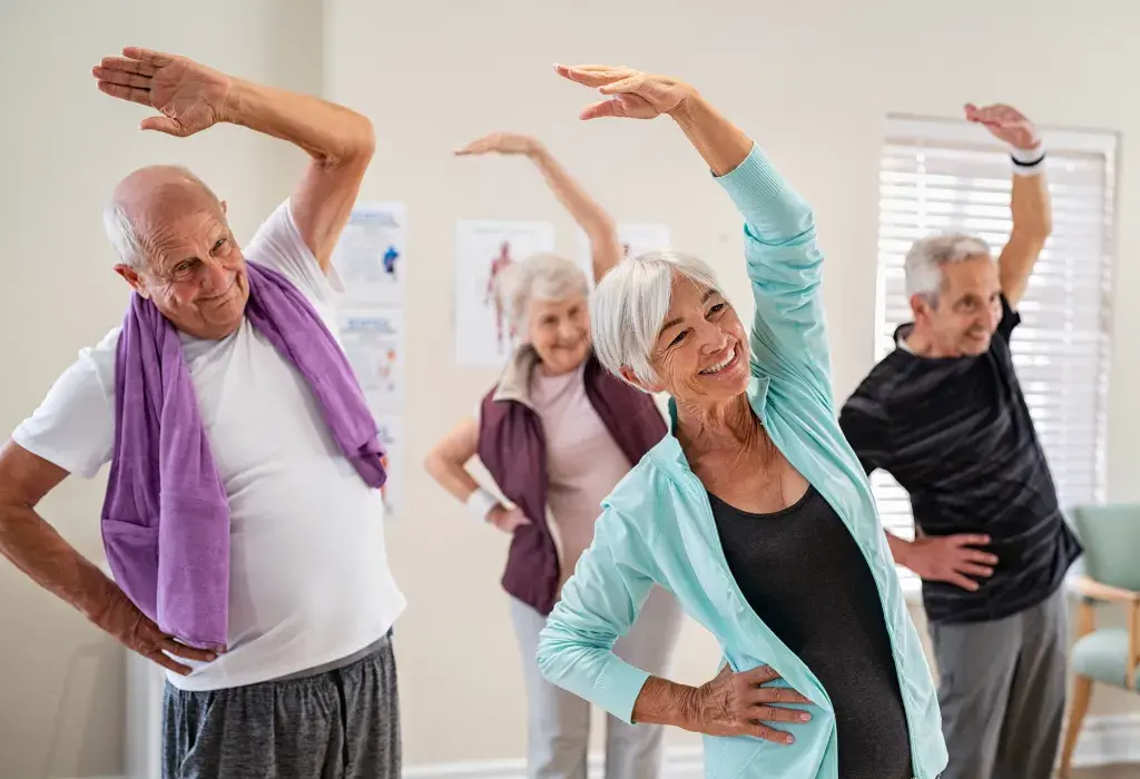 An elderly man smiling and participating in an active fitness class with other seniors at a Spring Living retirement home, showcasing assisted living wellness programs.
