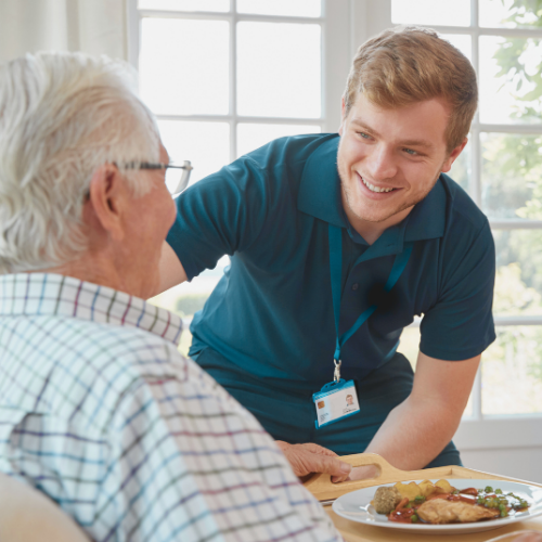 Senior living in a retirement home enjoying a home cooked meal served by staff