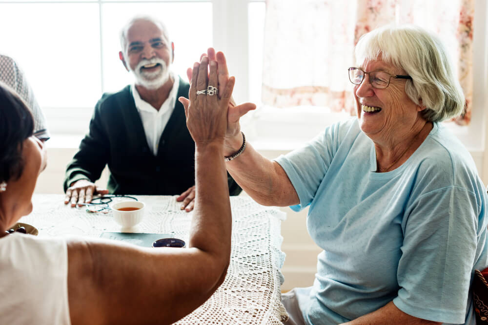 3 seniors smiling sitting at a table at a retirement home in Ontario