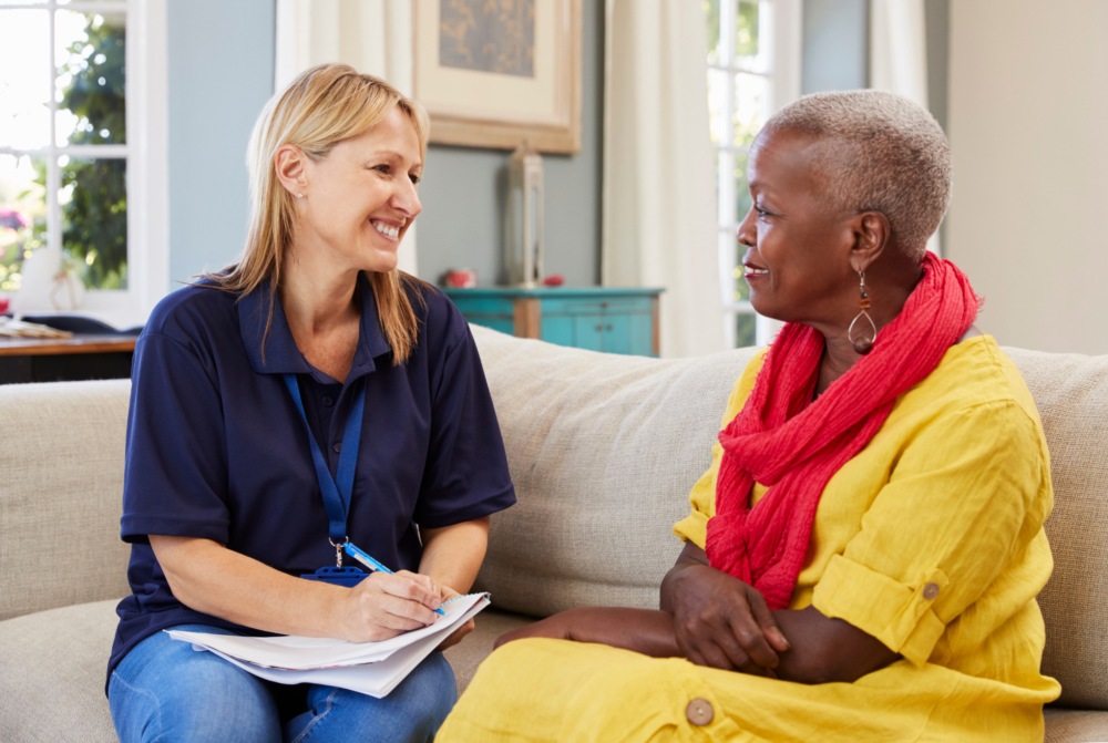 Senior chatting with young woman in a retirement home in Ontario. They seem happy and enjoying their conversation.